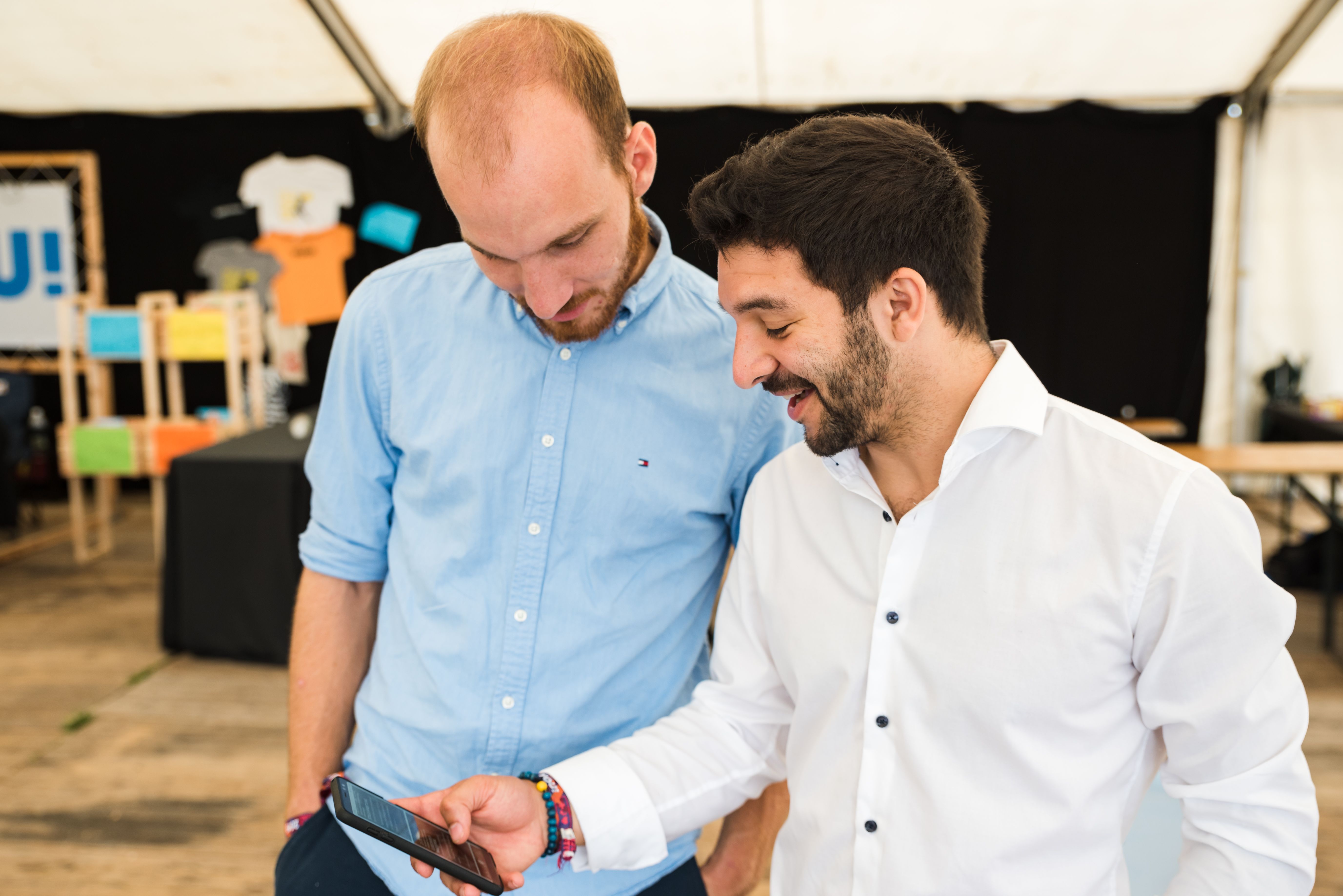 two young men are using their phones to search for Catholic events nearby