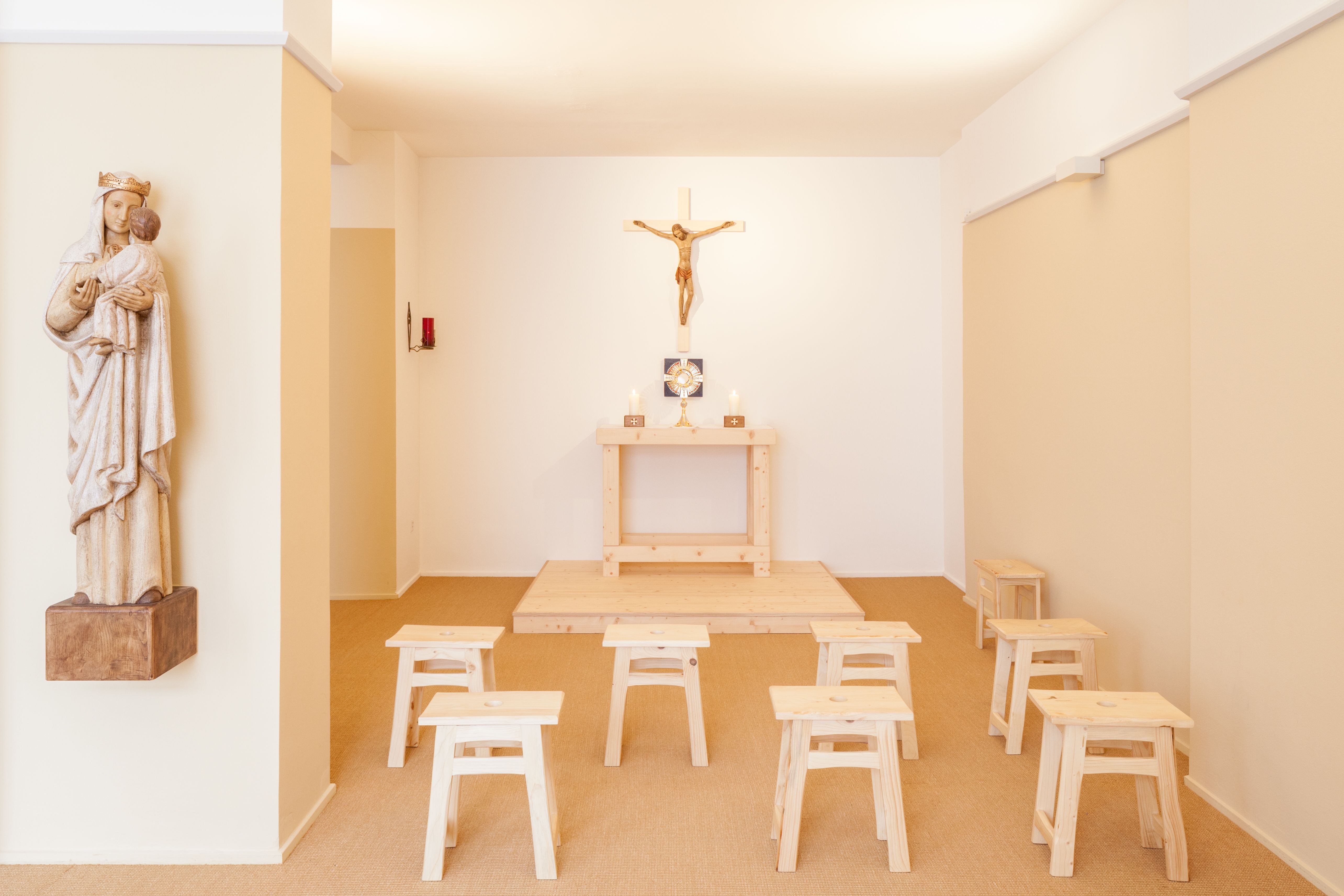 bright prayer room in Zürich with monstrance, cross, statue of Mary and armchairs inside